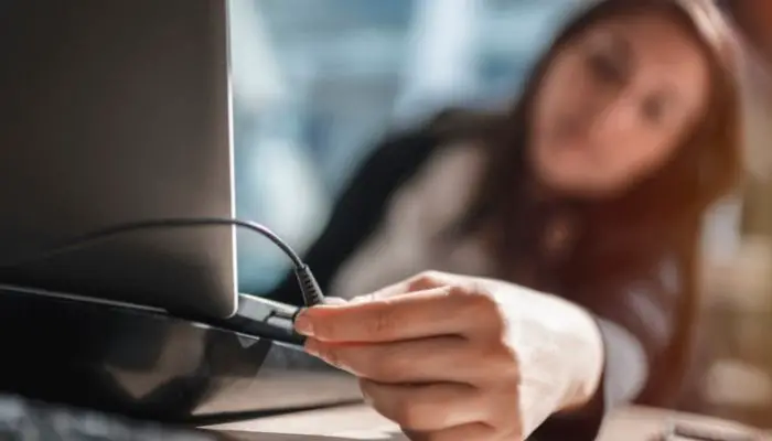A woman using a laptop while it is plugged in