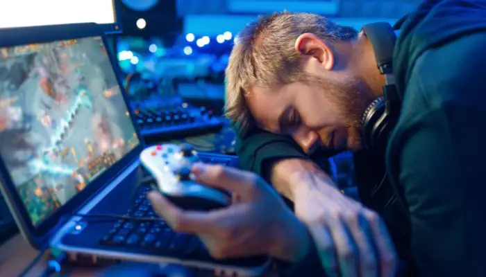 A gamer asleep beside his computer