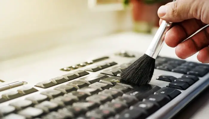 A keyboard being cleaned with a brush