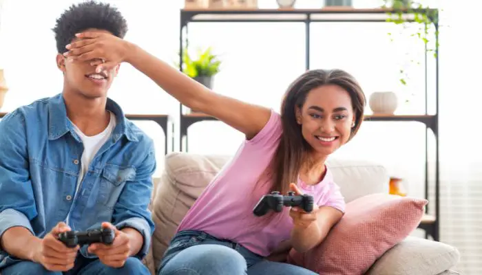 A man and a woman playing on a PlayStation